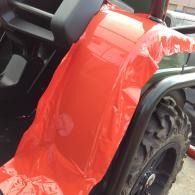 Red plastic fender cover draped over an ATV wheel in a garage or workshop