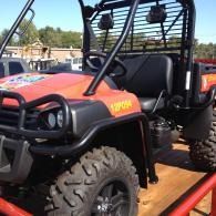 Orange off-road ATV with roll cage and large tires on a trailer outdoors