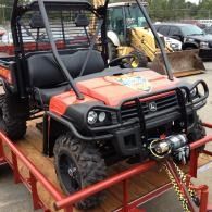 Red utility ATV on a trailer with black roll bars and front winch, parked outdoors.