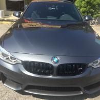 Front view of a dark gray BMW sedan parked outdoors in daylight