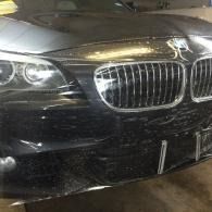 Front view of a black BMW sedan with a chrome grille in a garage