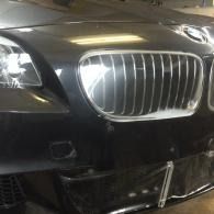 Close-up of a black BMW front grille and bumper in a garage