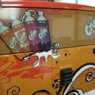 Orange soda-themed vehicle wrap with illustrated soda bottles and swirls