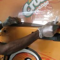 Hands in white gloves wrapping large orange plastic sheet