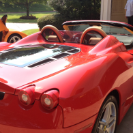 Red sports convertible with tan interior parked outdoors in sunlight