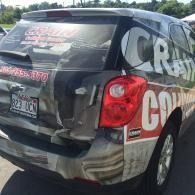 Black promotional SUV with large  lettering and red taillights in a parking lot