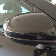 Close-up of a black car side mirror with a chrome trim strip