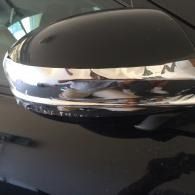 Close-up of a black car side mirror with a chrome accent reflecting the surroundings