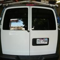 Rear view of a white van with closed double doors and a visible license plate.