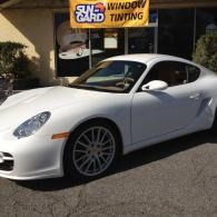 White sports car parked outside a window tinting shop.