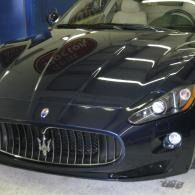 Black Maserati sports car parked indoors, front view with grille and headlights visible