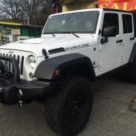 White Jeep Wrangler parked outdoors with large black off-road tires and a lifted suspension