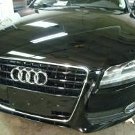 Black Audi sedan front view with chrome grille and headlights indoors