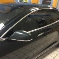 Black car parked indoors, side view with tinted windows and chrome trim