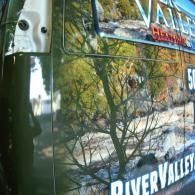 Bus window reflection with trees and the words “RIVER VALLEY” visible.
