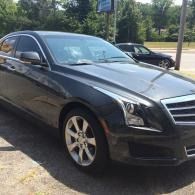Black sedan parked outdoors on a driveway, front-left view