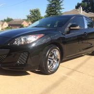 Black coupe parked in a driveway on a sunny suburban street