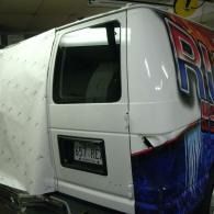 White cargo van with a tinted side window and blue-red graphics in a garage