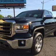 Black GMC pickup truck parked outdoors in front of a Ford Health sign