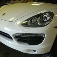 Front view of a white sports car showing the headlight, grille, and bumper