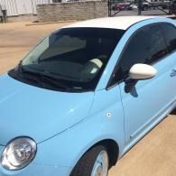 Light blue compact car parked outdoors in a driveway, front-left view.