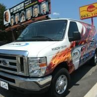 White promotional van with flame graphics parked outside a building.