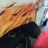 Person painting flame graphics on a vehicle wheel arch