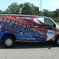 Branded Russaw heating and cooling service van parked outdoors, blue and red graphics on white vehicle