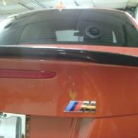 Rear view of a red BMW M4 with a black spoiler and rear window visible