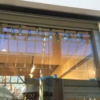 Glass storefront with reflections and hanging lights under a covered walkway