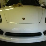 Front view of a white Porsche in a dim garage
