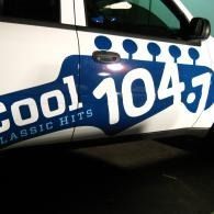 White car door with blue “Cool 104.7” classic hits radio logo.