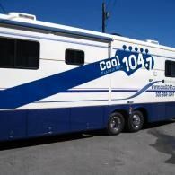 Blue-and-white “Cool 104.7” radio station bus parked outdoors
