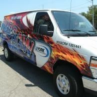 White cargo van with colorful graffiti-style graphics parked outdoors in sunlight