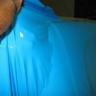 Hand holding a bright blue plastic sheet or bag against a dark background