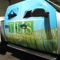 Blue car door with TLS Environmental Solutions logo and green grass graphic