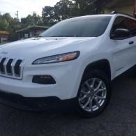 White Jeep SUV parked outdoors on a driveway under a shaded carport