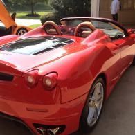 Red convertible sports car parked outdoors, rear view with black interior and silver wheels