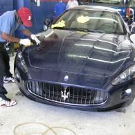 Person washing a dark blue Maserati sports car in a garage