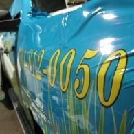 Blue vehicle side with yellow “0050” lettering and white/green graphics, close-up view