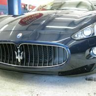 Close-up of a dark blue Maserati front grille and headlights in a garage
