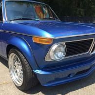 Blue vintage car parked outdoors, front view with chrome grille and white wheels