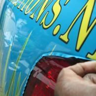 Close-up of a hand wiping a red car tail light with blue body text nearby