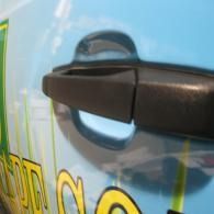 Close-up of a black car door handle on a light blue vehicle