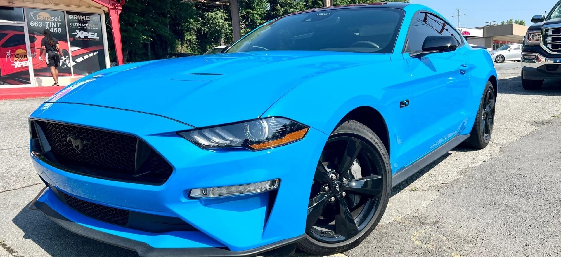 Bright blue Ford Mustang parked outdoors on a sunny lot