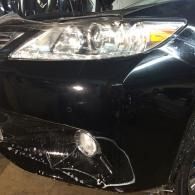Front of a black car with a damaged lower bumper and fog light area