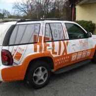 White-and-orange HELIX-branded SUV parked outdoors beside a building.