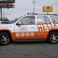 Orange-and-white taxi with large “HELP” text on the side, parked on a street.