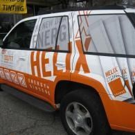 White and orange HELEX-branded SUV parked outdoors beside a storefront window