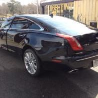 Black Cadillac coupe parked outdoors beside a yellow container type building.